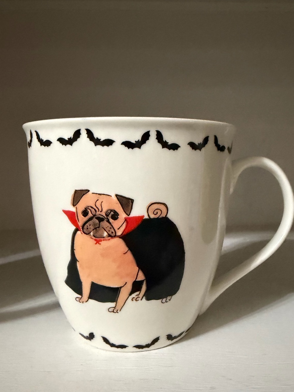 A contemporary Milly Green ceramic mug featuring a pug in a vampire costume.